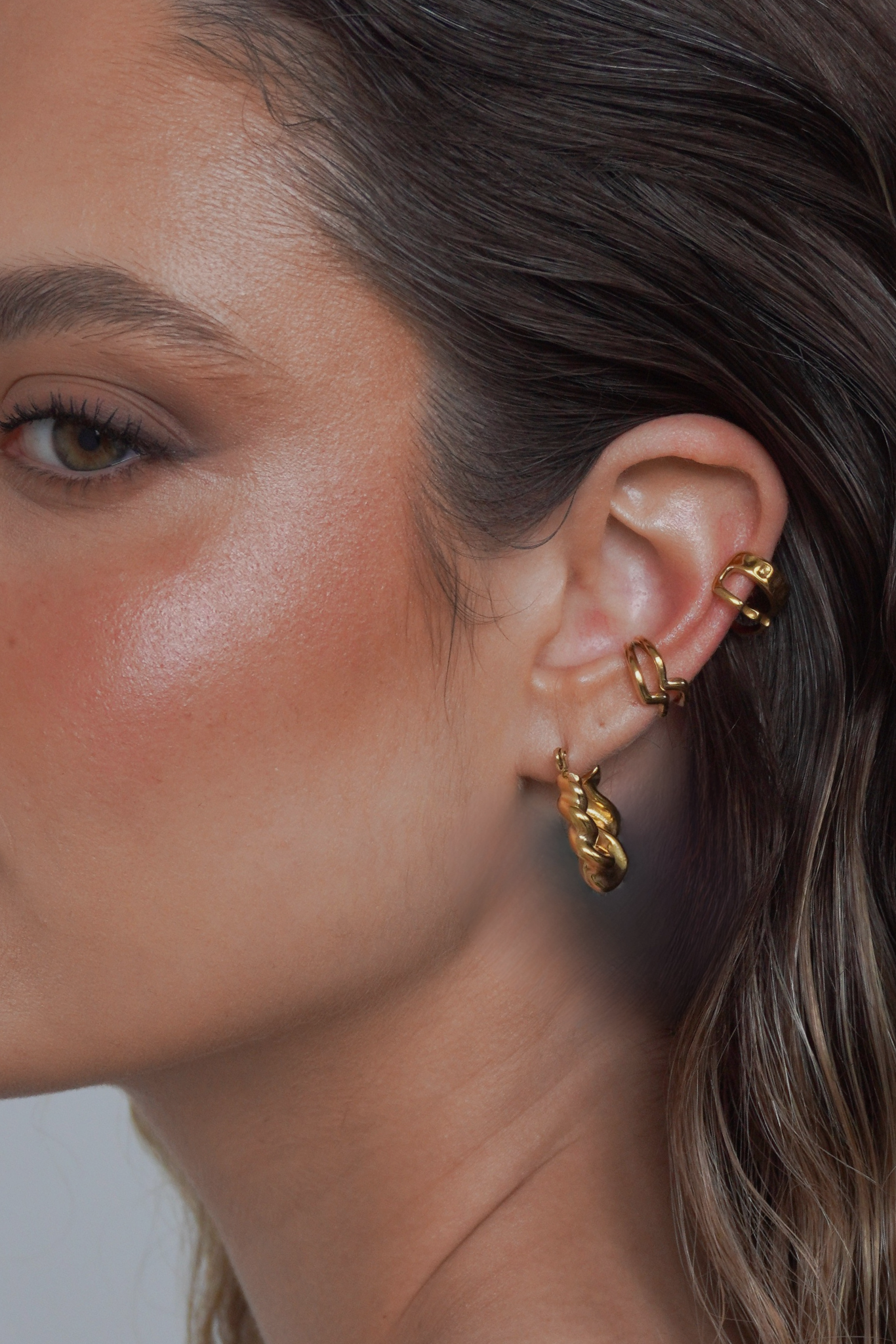 Model wearing gold hammered ear cuff styled with another ear cuff and hoop earrings by MILA GIRALDO.
