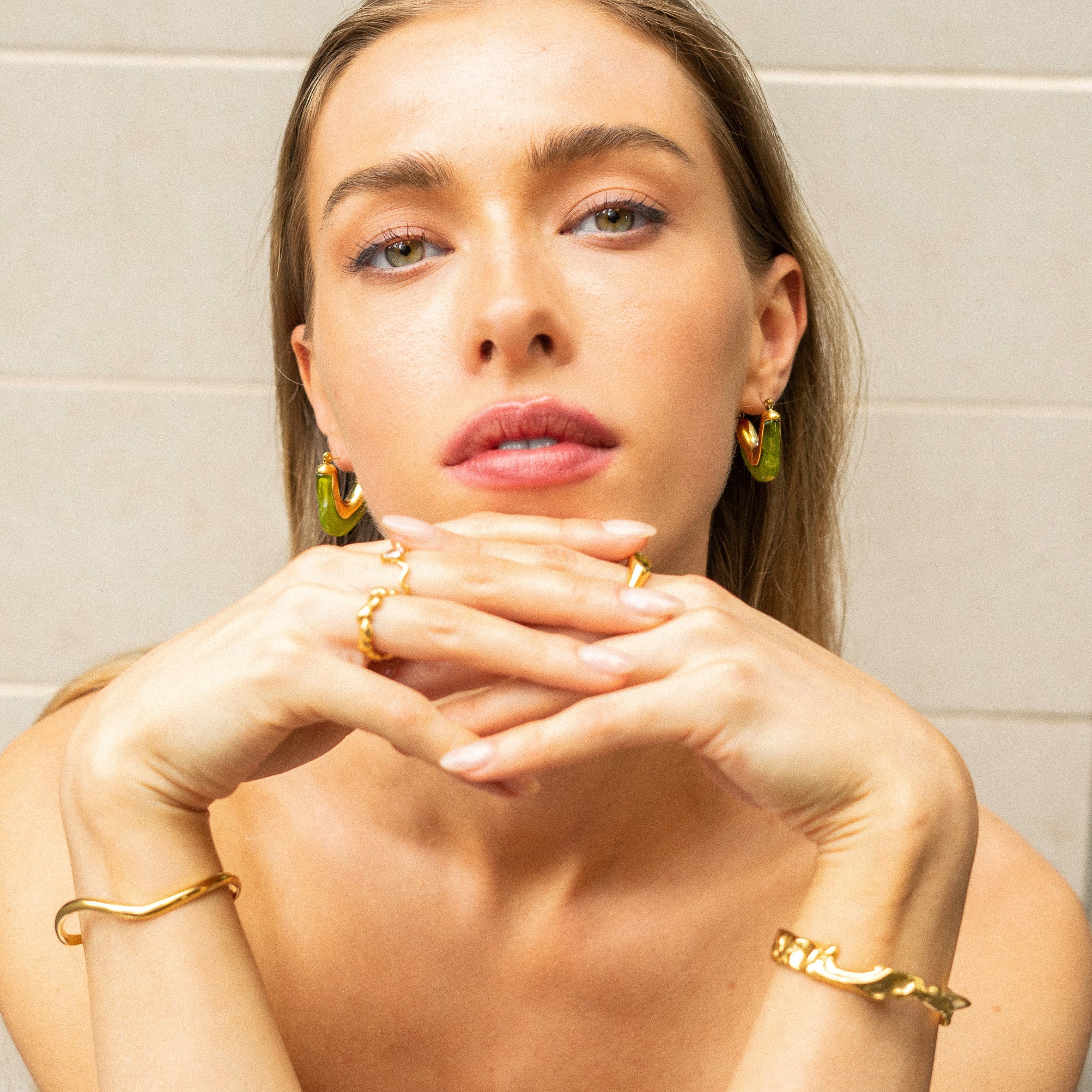 Model wearing vivid green Mia Resin Hoops by Mila Giraldo, styling bangles and rings for a cohesive, fashion-forward jewellery look.