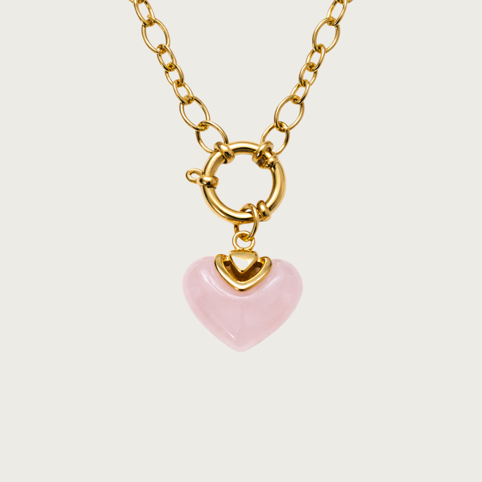 Gold necklace with a pink heart-shaped pendant on a chunky chain