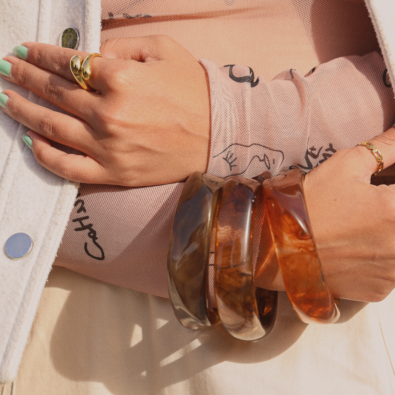 Crossy Ring – 18k Gold PVD Plated Stainless Steel – Styled on Model With Stacked Bangles and an Adjustable Ring – Sculptural Crossover Teardrop Band Ring in Lifestyle Shot – Mila Giraldo Jewellery Australia
